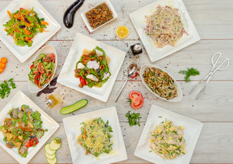 flat lay composition of restaurant menu. top view of delicious vegetable salds mixed with meat or chicken and covered souces, herbs and spices.