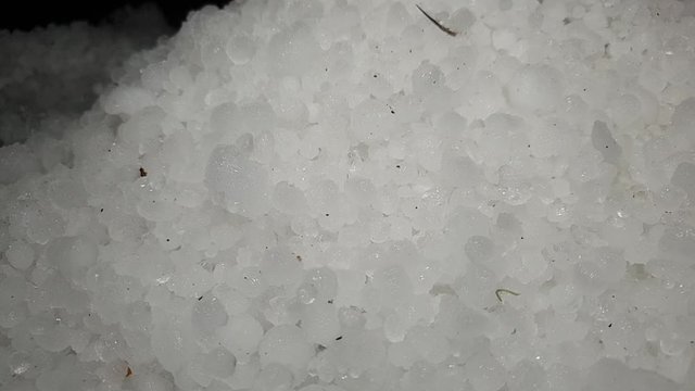 White hail storm ice balls being shoveled and moved in a pile for cleanup and removal