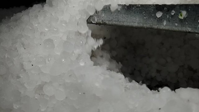 White hail storm ice balls being shoveled and moved in a pile for cleanup and removal