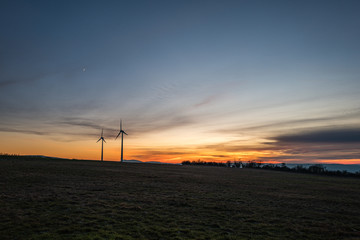 Obraz premium zwei einsame windräder im abendlicht