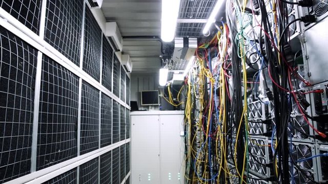 Inside room with data centers and cables. Stock footage. Room with data centers, cables and solar panels to absorb bright artificial lighting