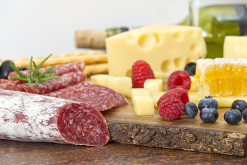 Beautiful sliced food arrangement close-up photo. Italian style antipasto plate, cheese, ham, salami, rosmarin, prosciutto