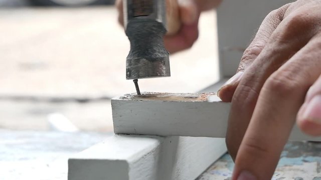 The man hand manual saw cutting wooden, use a hammer to strike a nail a wooden fence.