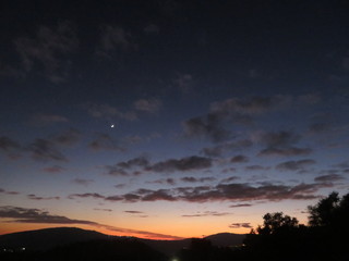 Fototapeta na wymiar moon and first star in sun set sky over mountains