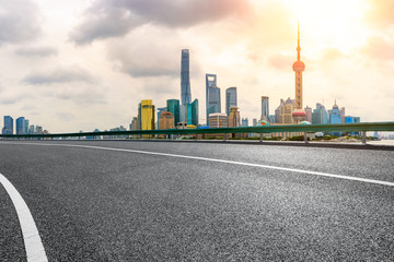 Empty asphalt road and city skyline view at sunset in Shanghai