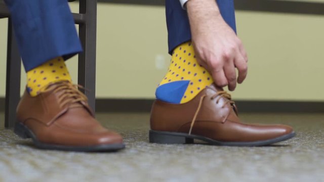 Man putting on Brown Dress Shoes with Yellow Socks