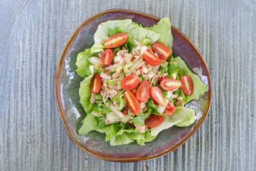 Spicy tuna and vegetables salad in Thai style in ceramic plate put on the stone table background. Top view. Thai cuisine