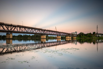 Transport bridge over a river with coloured rays in the sky from sunset.