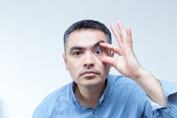 Obraz premium Portrait of a man in a blue shirt showing an oculist on a white background