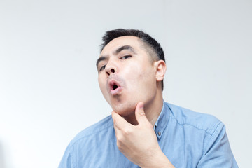 Portrait of a man in blue shirt looking at shaved face on white background