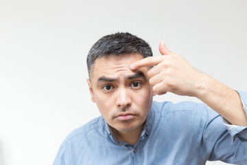 Portrait of a man in a blue shirt looking at the forehead of wrinkles on white background