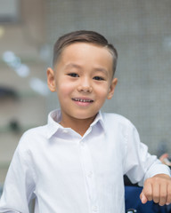 Close-up portrait of an attractive handsome smiling boy looking at camera after a haircut on white shirts. Beautiful boy. Six year old boy smiling and having fun