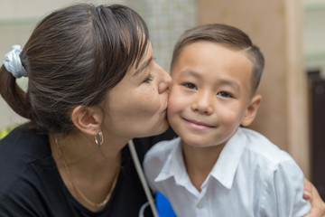 Happy mother and son, mom kisses her son