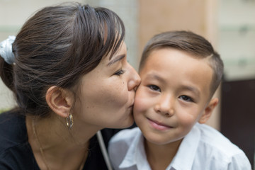 Happy mother and son, mom kisses her son