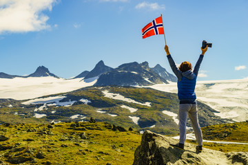 Tourist with camera and flag in Norway mountains