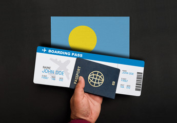 Hand holds passport and boarding pass with flag of Palau