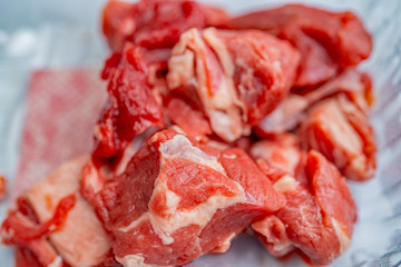 A plastic container of raw diced lamb meat with a close up and selective focus on a particular piece
