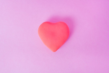 red heart on a pink background. the heart is located in the center of the frame..
