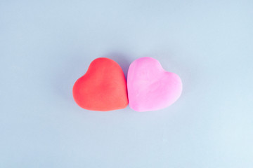 red and pink heart on a blue background. both hearts are located in the center of the frame..