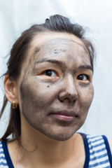 Women's black soap. Beautiful young girl wash her face with black soap on a white background and funny poses on the camera