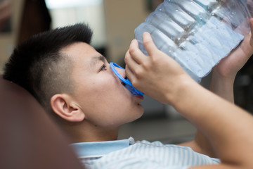 A man drinks water from a five-liter plastic bottle
