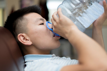 Obraz na płótnie Canvas A man drinks water from a five-liter plastic bottle