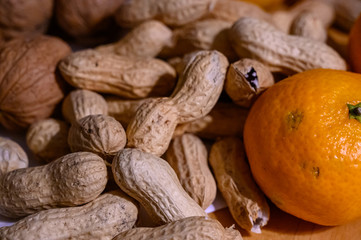 Peanuts nuts tangerines and apples on a table in close-up