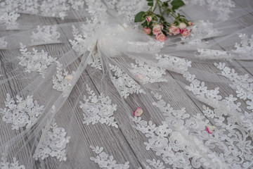 White wooden background with white spring flowers roses and lace ribbon. Happy womans day. The texture of lace on wooden background.