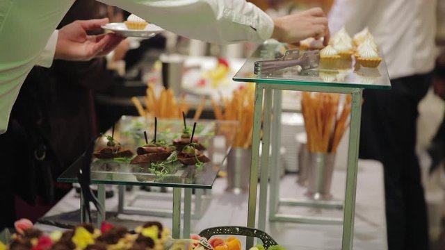 Waiters put luxury snacks with red caviar from tray on table preparing for wedding dinner extreme close view slow motion