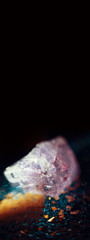 Raw gemstones and a candle in a dark background with magical glitters