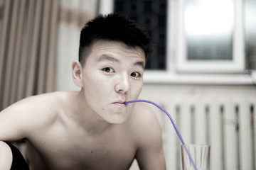 A young guy drinks water from a glass