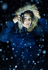 young girl at night in jackets on the background of snowfall