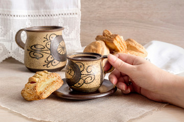 Cakes with fillings on the table close-up and hand holding a cup with coffee