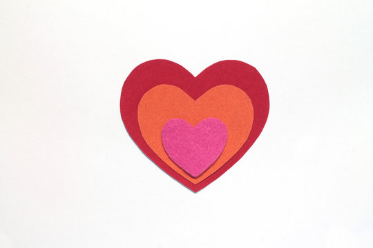 Red, orange and pink hearts of different sizes lie on each other on an isolated white background. Stock photo for Valentine's Day.