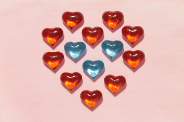 Fototapeta na wymiar Frame of red hearts with blue hearts in the center on a pink background. Background for Valentine's Day. Love, romance, festive mood. Stock photo with empty space for your text.