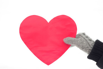 Female hand in gray mittens holds a big red heart.  Winter romantic mood. Stock photo for valentine's day. Celebration background for web, print and wallpaper.  
