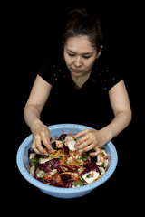 woman preparing salad with fresh vegetables. Preparation of tasty and healthy food on a black background
