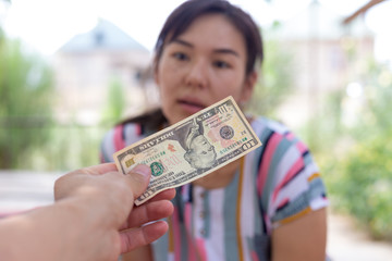 Offer dollar bills. A man offers a girl money for sex