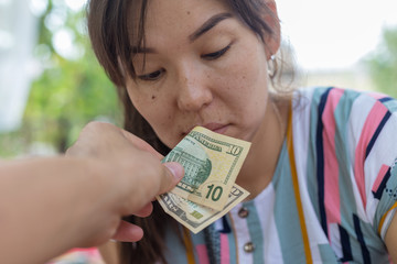 Offer dollar bills. A man offers a girl money for sex