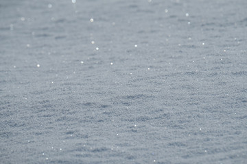Bright sunny day with sparkling glittering fresh fallen snow and bokeh.  Beautiful shiny blanket of snow texture, background and wallpaper. 