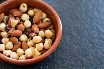 Bowl with dry fruit. almonds, peanuts and hazelnuts in a bowl with raisins. dried fruit for healthy vegan breakfast. Dried autumn fruits to be used for proper nutrition. Health and wellness with nuts