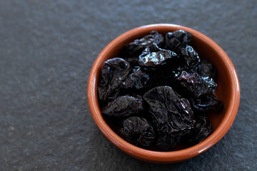 bowl of prunes on a black stone table. healthy and good vegan breakfast and snack