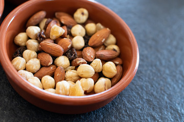 Bowl with dry fruit. almonds, peanuts and hazelnuts in a bowl with raisins. dried fruit for healthy vegan breakfast. Dried autumn fruits to be used for proper nutrition. Health and wellness with nuts