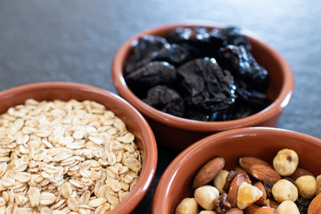Healty, vegetarian dried fruit breakfast. Set of bowls with dried fruit to enrich a healthy vegan breakfast. Oats, almonds and plums to be included as a snack for a diet for beauty and health behavior
