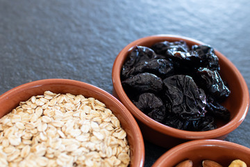 Healty, vegetarian dried fruit breakfast. Set of bowls with dried fruit to enrich a healthy vegan breakfast. Oats, almonds and plums to be included as a snack for a diet for beauty and health behavior