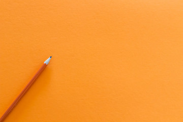 orange pencil on a yellow background. Set up for advertising and creativity banners. Warm yellow...