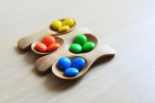 colorful button-shaped candies coated chocolate sweets in wooden spoon on wood table