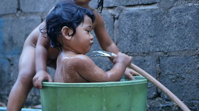 Two Baby girl bathed in a basin. Happy laughing baby taking a bath and playing outdoor. baby in little basin