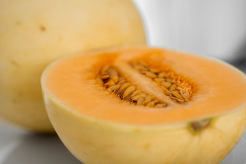 Fresh sweet orange melon on the white plate as a background with a selective focusing. Useful and vitamin-rich food. Vegeterian.