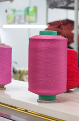 bobbins with pink elastic yarn on a knitting machine in the shop at work